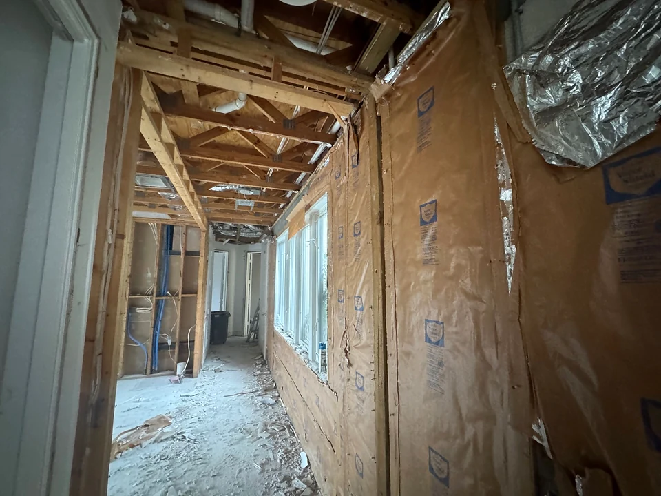 Hallway with exposed ceiling framing and wall sheathing during interior preparation