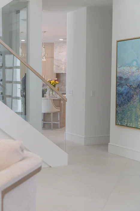 Glass staircase and art with a view into the kitchen