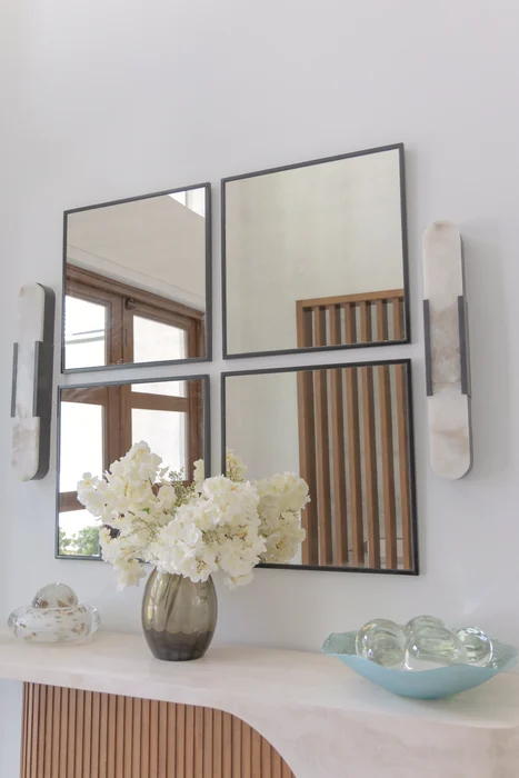 Entry mirrors, stone sconces, and floral arrangement