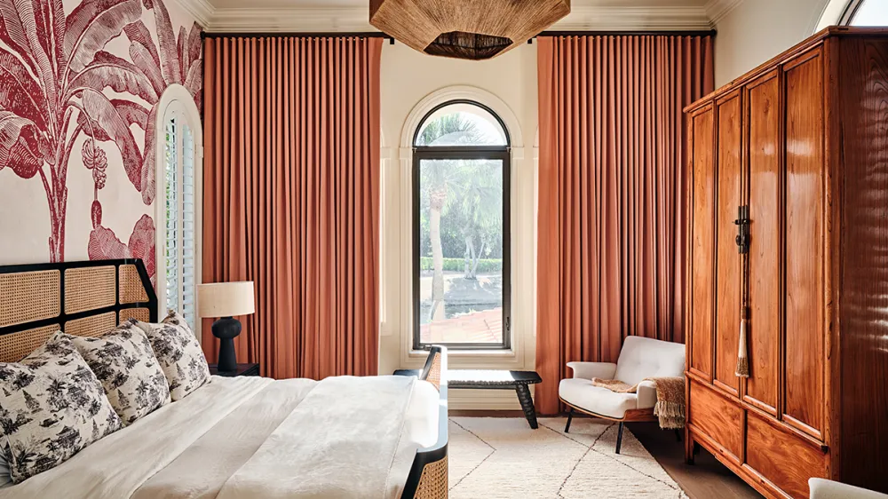 Golden Lion Estate bedroom with coral curtains, botanical wallpaper, and a wood armoire